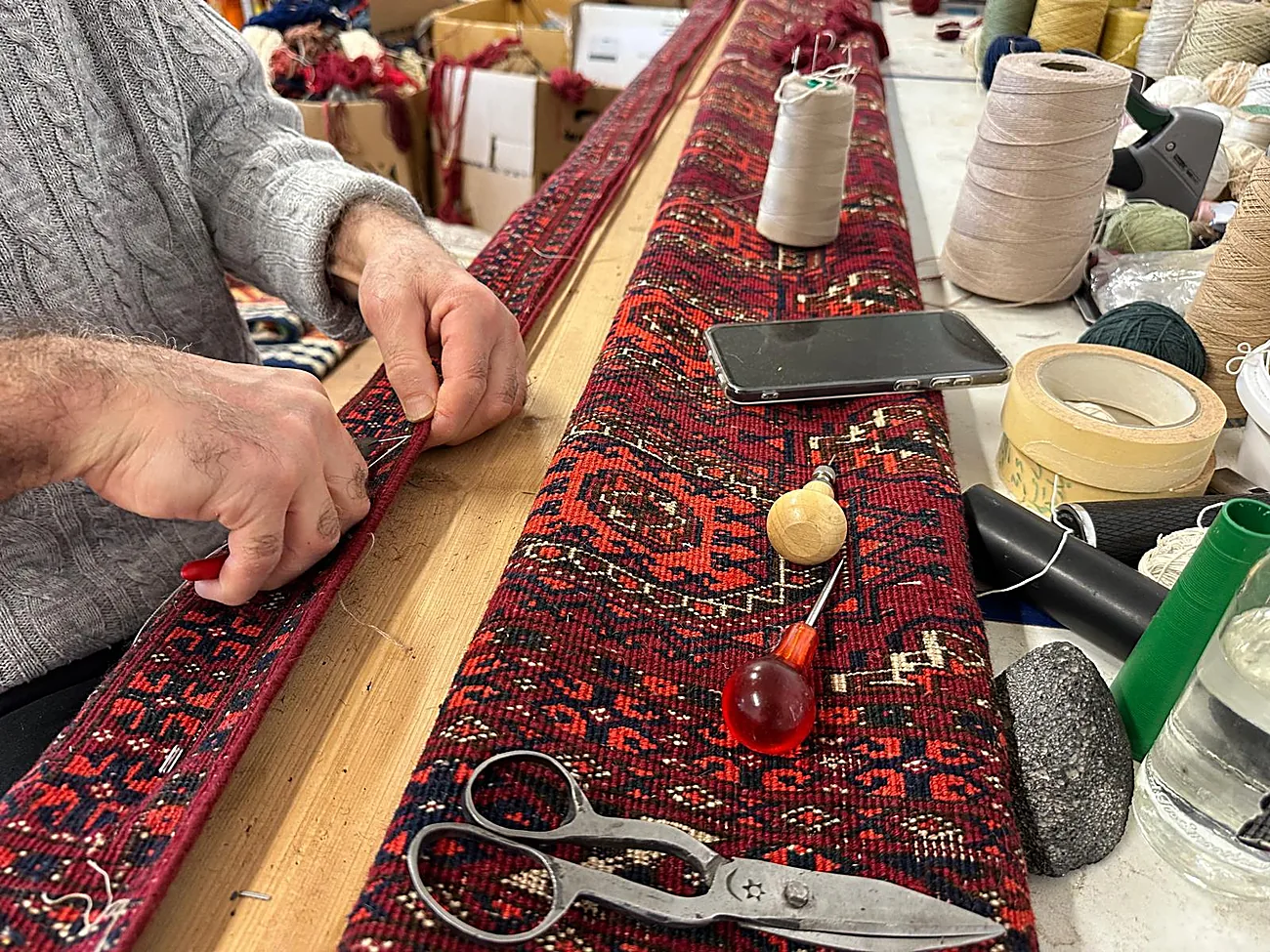Réparation des franges d'un tapis à la main en atelier